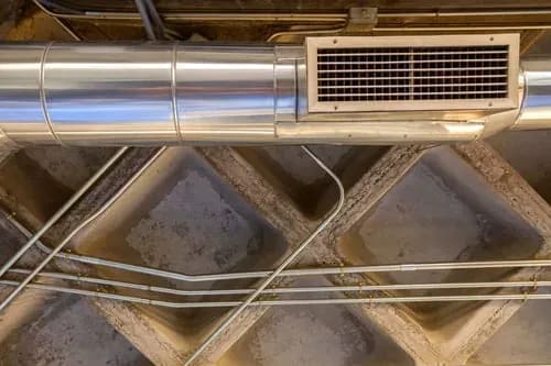 Metal HVAC duct run and ceiling supply vent inside a building interior