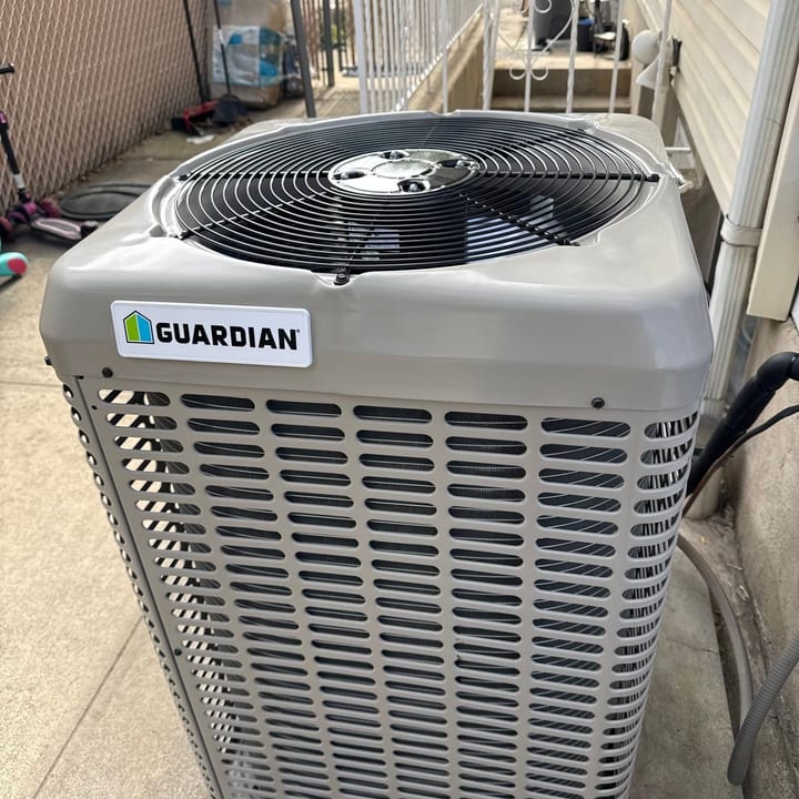 Guardian air conditioning condenser installed on a paver pad beside a house
