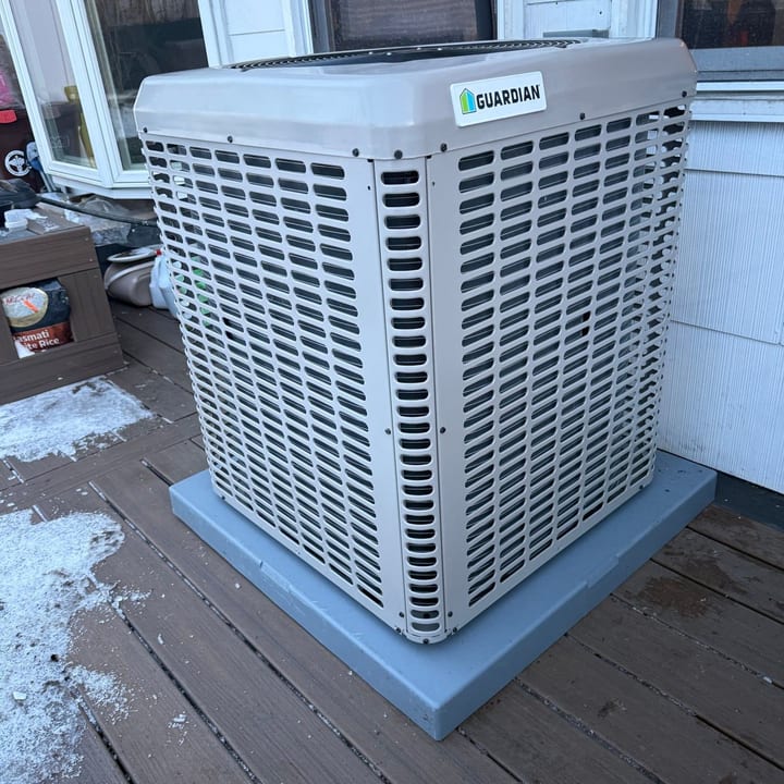 New air conditioning condenser on a composite pad on a backyard deck
