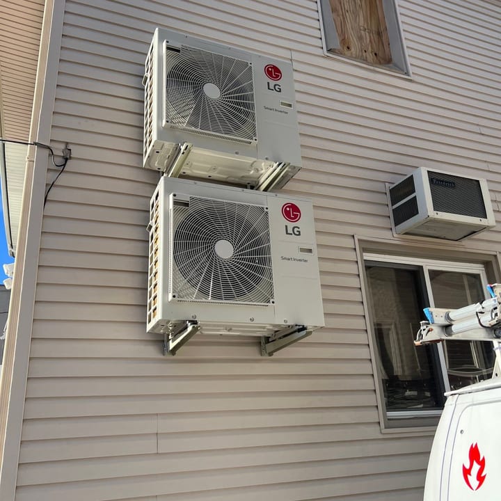 Two LG mini-split outdoor units wall-mounted beside the window units they replace