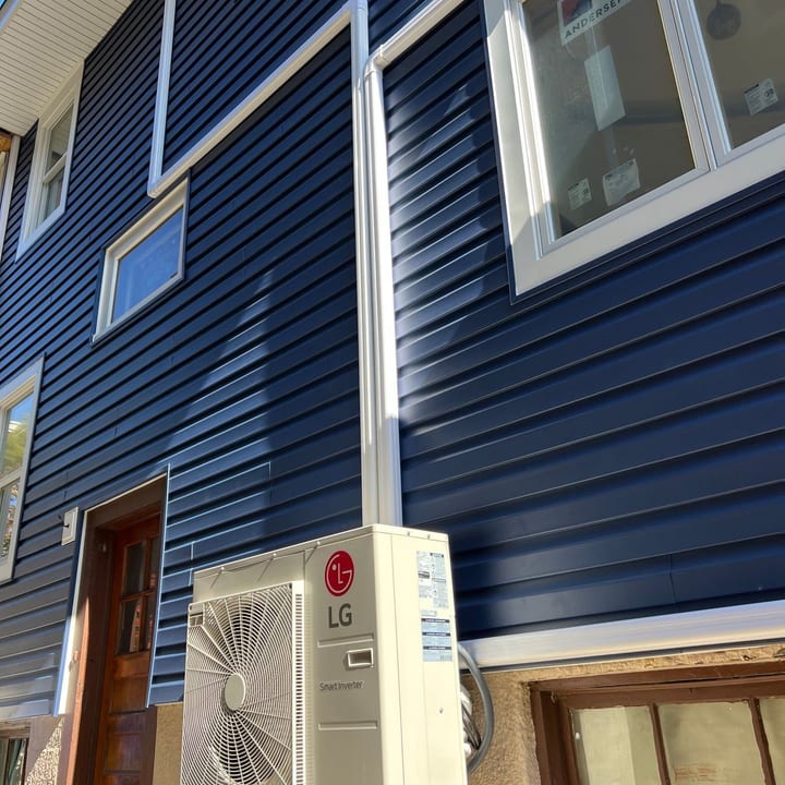 LG mini-split outdoor unit mounted on the blue siding of a home