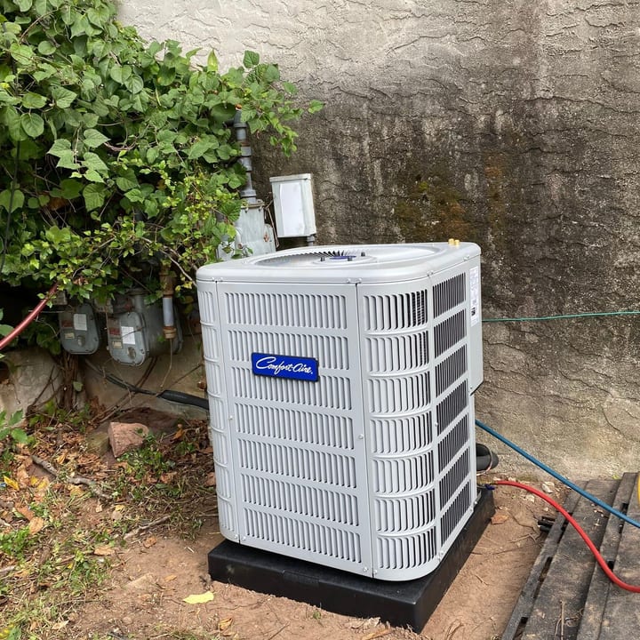 New condenser unit installed on a pad in a backyard