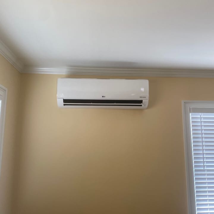 Ductless mini-split indoor unit mounted above a window in a living room
