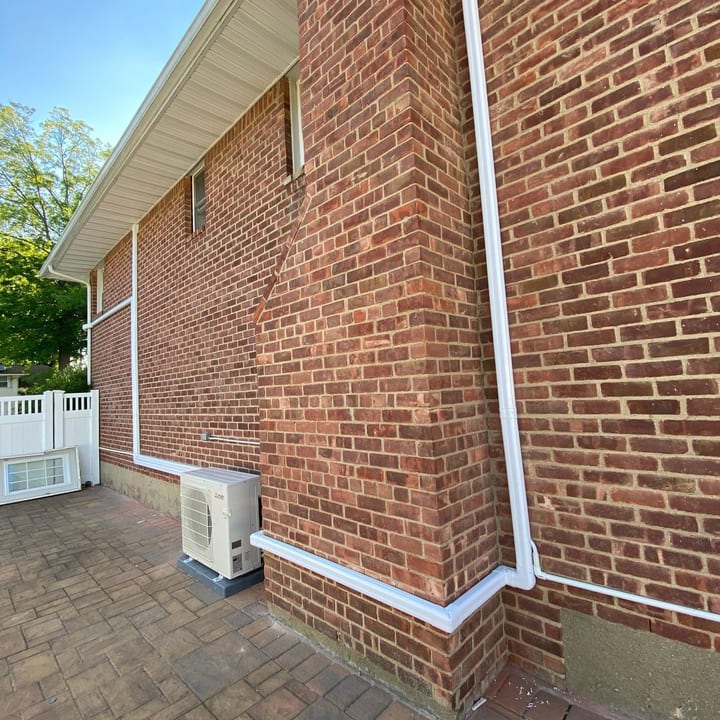 Line-set cover running down a brick wall to a mini-split outdoor unit