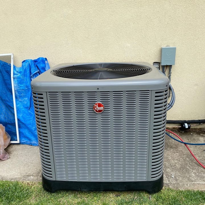 Rheem condenser on a pad in a backyard lawn